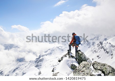 mountaineer on the top of a mountain in the background of the landscape of snowy mountains