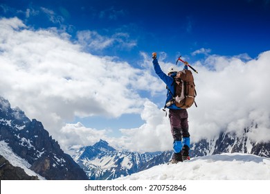 Mountaineer Reaches The Top Of A Snowy Mountain In A Sunny Winter Day