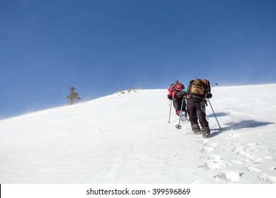 Mountaineering Group Of Tourists Climbing Up The Snow Covered Mountain. The Steep Slope And A Snowstorm On A Clear Day