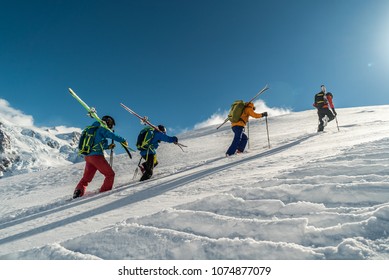 Mountaineers walking up along a snowy ridge with the skis in the backpack. Skier on the climbing track for freeride-descent. Backcountry skiers. ski free rider climbs the slope into deep snow powder. 