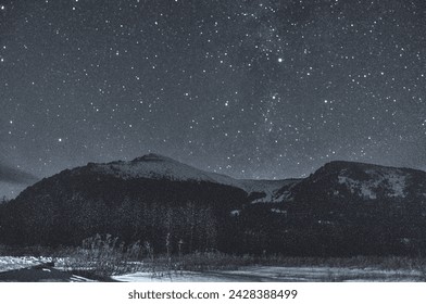 A mountainous landscape blanketed in pristine snow, illuminated by a starry night sky creating a tranquil and atmospheric atmosphere. Russia, Siberia, Altai mountains. - Powered by Shutterstock