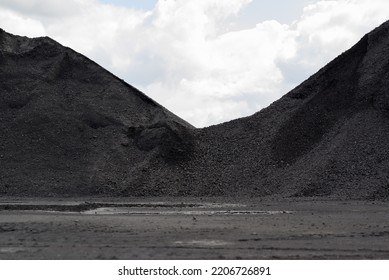 Mountains Of Black Coal In A Concept Of Energy Crisis And Energy Shortage In The Foreground Puddles With Grey Sky