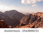 The mountains are brown and rocky, with a clear blue sky in the background. The view is breathtaking and serene, with the mountains stretching out as far as the eye can see