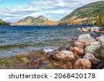 The mountains called The North and South Bubbles display beautiful fall color as seen from the banks, strewn with boulders, of Jordan Pond in Acadia National Park on Mt. Desert Island, Maine.