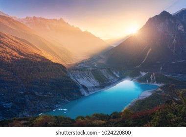 Mountains and lake with blue water at sunset in Nepal. Majestic landscape with high mountains, lake, lightened hills, rocks, yellow sunlight and blue sky. Bright sunny evening. Travel. Nature - Powered by Shutterstock