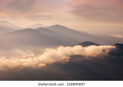 Mountains in low dense fog at morning sunrise. Beautiful landscape with mountain peaks in fog. Mountain valley in clouds. - Shutterstock ID 2184093097