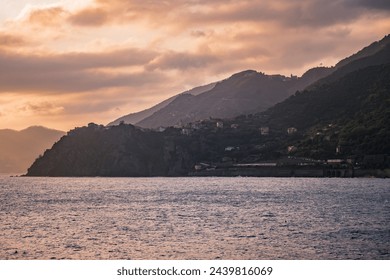 Mountains with mediterranean Corniglia village in lowlight and gradient in horizon at sunset, Cinque Terre ITALY