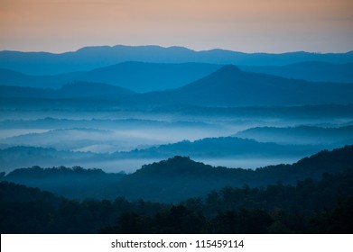 The mountains on the Blue Ridge Parkway welcome the morning with light and mist. Fog is forming in the valley as the sun comes up lighting up the day.