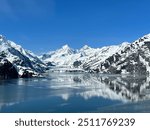 Mountains reflect off the ocean with John Hopkins Glacier, Mount Orville and Mount Wilbur in the background.   Glacier Bay National Park. Alaska