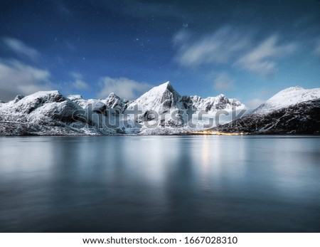 Mountains and reflections on water at night. Winter landscape. The sky with stars and clouds in motion. Nature as a background. Norway - travel