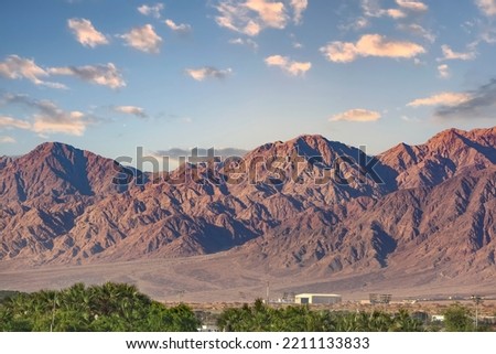 Mountains ridge Eilat. Walk through the mountains near the Gulf of Red Sea in Israel. Mountain range and clear day skies. Fantastically beautiful landscape desert, palm tree, clouds and blue sky. 