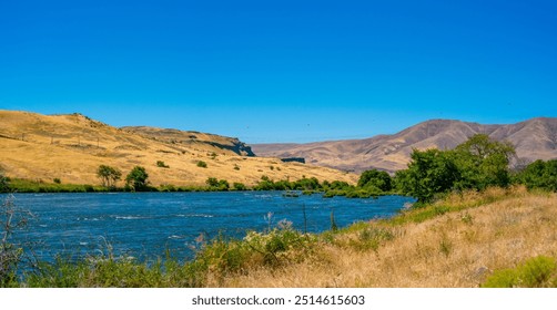 mountains and a river with a few birds flying over it - Powered by Shutterstock