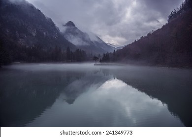 Mountains And Sky Reflection In A Lake With Forest.