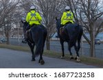 Mounted police officers in bright green jackets horseback riding patrolling city streets during covid-19 coronavirus outbreak pandemic quarantine. Essential services workers. Selective focus.