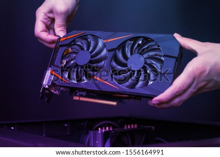 Mounting a modern graphic card to gaming computer. High performance graphics card with two coolers. The hands place the card in the computer case.