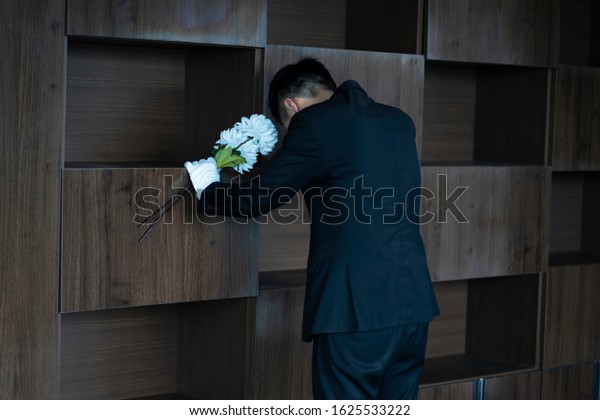 Mourner crying with\
flowers at funeral
