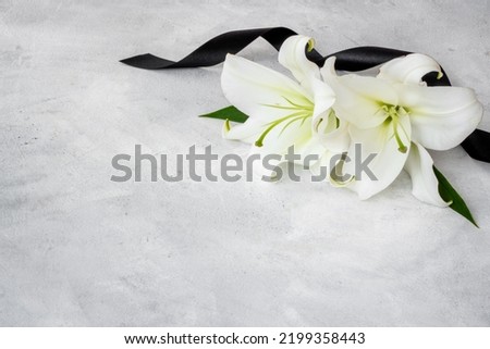 Mourning or funeral concept with white liles and black ribbon