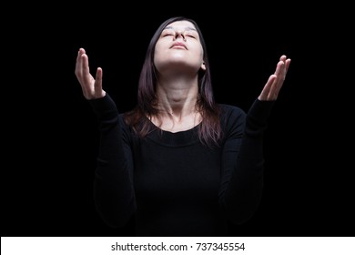 Mourning woman praying, with arms outstretched in worship to god, head up and eyes closed in suffer, on black background. Concept for religion, faith, prayer, grief, mourn, pain, depression. - Shutterstock ID 737345554