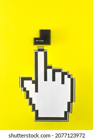 the mouse cursor hand points to the black enter button from the keyboard. yellow background. copy space.
