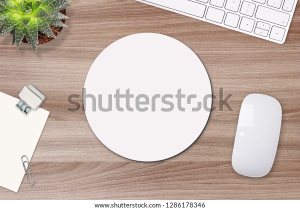 Mouse pad mockup. Round white mat on the table\
with props, mouse and\
keyboard