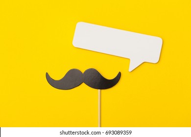 Moustache on a stick with a speech bubble on a bright yellow background