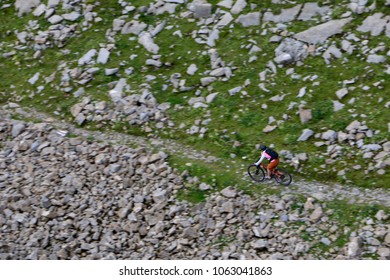 A Moutain Biker Riding Downhill On A Single Trail Between Rocks