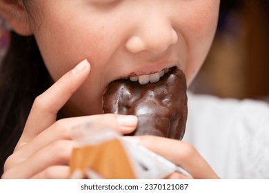 The mouth of a child eating an eclair - Shutterstock ID 2370121087