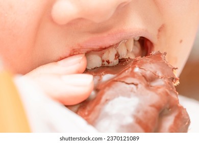 The mouth of a child eating an eclair - Shutterstock ID 2370121089