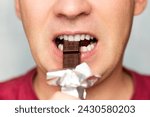 Mouth of man eating chocolate against blue background. A man