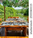 Mouthwatering culinary experience overlooking Saint Naum Springs in National Park Galicica at Lake Ohrid, North Macedonia. Sheltered table by leafy canopy, providing shade and touch of natural beauty