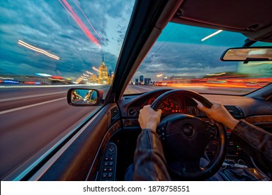 Movement Of The Car At Night At High Speed View From The Interior With Driver Hands On Wheel. Concept Spped Of Life. Long Exposure Photo.