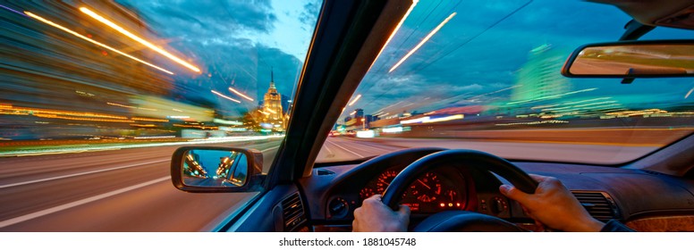 Movement of the car at night at high speed view from the interior with driver hands on wheel. Concept spped of life. Long exposure photo.