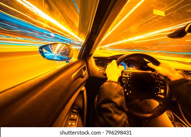 Movement Of The Car At Night At High Speed View From The Interior With Driver Hands On Wheel. Concept Speed Of Life.