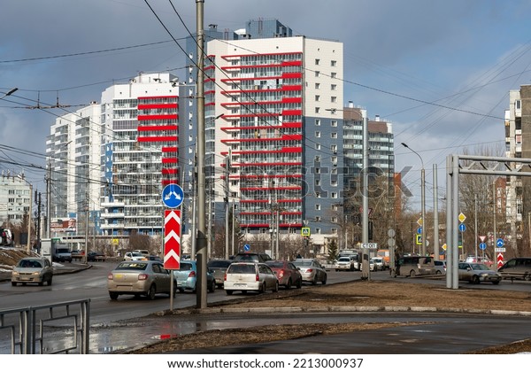 The movement of cars at the crossroads in\
the winter city. Russia Krasnoyarsk March 2022. Large high arch\
above the road with traffic lanes\
signs.