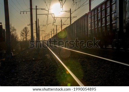 the movement of a freight train along the rails against the background of the bright sun