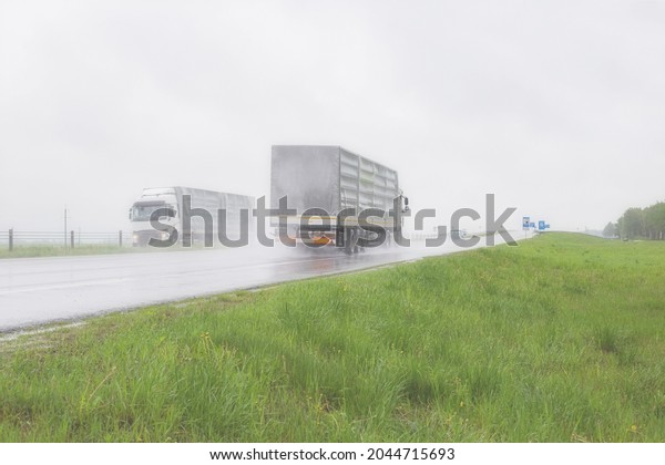 The movement of\
trucks of trucks with a semi-trailer and cars on a wet road in rain\
and fog and in poor visibility. Road safety concept. Copy space for\
text, transportation