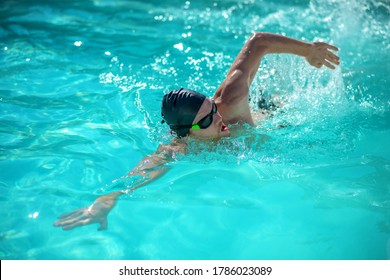 Movement in water. Man in black swimming cap floating on his side with his mouth open in pool - Powered by Shutterstock