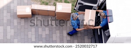 Movers carrying heavy boxes while moving with truck