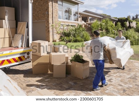 Movers carrying sofa from moving van to house