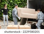 Movers loading heavy beige couch in van