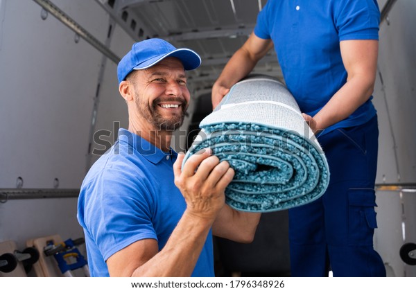 Movers Moving Carpet From\
Truck Or Van