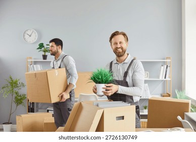 Movers packing boxes for office relocation delivery. One holds a plant as another carries cartons, coordinating transport and logistics. Concept professional team, reliable service, and care. - Powered by Shutterstock - Get 15% off with code: PIKWIZARD15