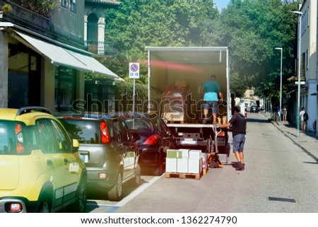 movers unload boxes from a van on a city street, cityscape
