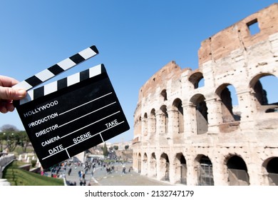 Movie clapper board in front of Coliseum monument in Rome, hands holding film slate defocused background
