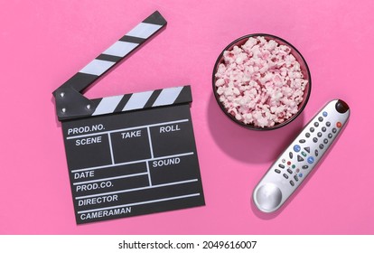 Movie Clapper Board, Popcorn Bowl, Tv Remote On Pink Background With Deep Shadows. Entertainment Industry. Top View