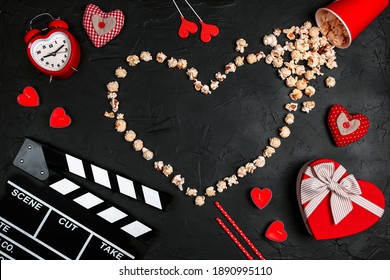 Movie clapper board, popcorn heart, gift box, candles and other love objects on black background with copy space. Valentine's Day, date and romantic evening concept. Love story movies.