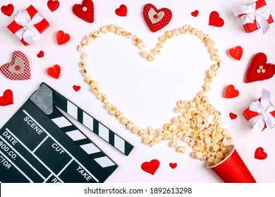 Movie clapper board, popcorn heart, gifts and candles on white background with copy space. Valentine's Day, date and romantic evening concept. Love story movies.