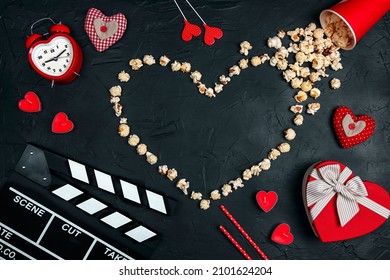 Movie clapper board, popcorn heart, gift box, candles and other love objects on black background with copy space. Valentine's Day, date and romantic evening concept. Love story movies.