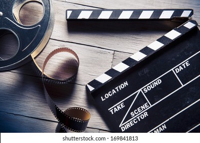 Movie clapper and film reel on a wooden background