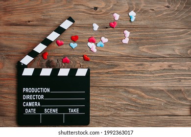 Movie Clapperboard And Confetti Hearts On A Wooden Background. Flatlay. Copy Space. Movie Night, Date, Valentine's Day